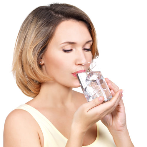 Beautiful young smiling woman with a glass of water on a white background